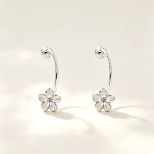 Gros plan de boucles d'oreilles en argent en forme de C avec un motif de fleur délicat