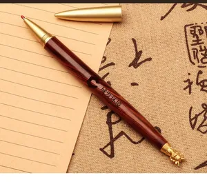 Detailed view of a luxury brass and wood pen with a decorative dragon head finial.