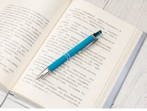Close-up of blue retractable ballpoint pen with stylus tip placed on an open book