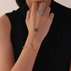 Detalle de cadena de mano dorada con dijes de flores coloridas en modelo