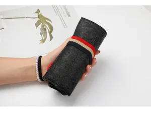 Close-up of dark grey felt pencil case roll with striped elastic band held in hand