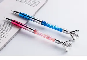 Macro view of blue and pink metal pens with large diamonds and glitter quicksand barrels.