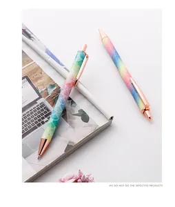 Detail of a rainbow glitter retractable ballpoint pen with elegant rose gold metal accents