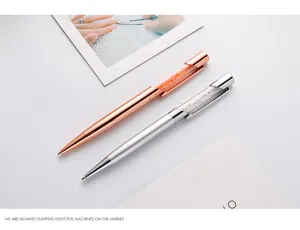 Vue détaillée de stylos à bille métalliques rose doré et argent remplis de cristaux.