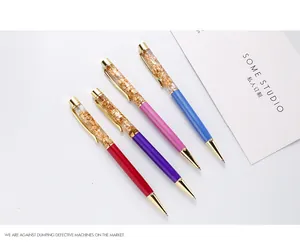 Close-up of gold foil floating in four colorful rotating metal ballpoint pens