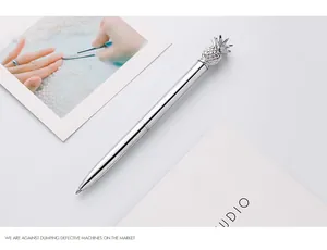 Close-up detail of silver metal ballpoint pen featuring a decorative pineapple topper