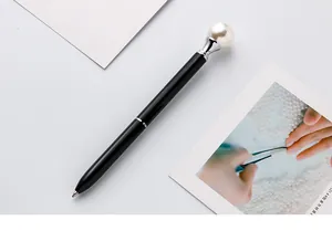 Detailed view of an elegant black metal ballpoint pen with a large white pearl topper.