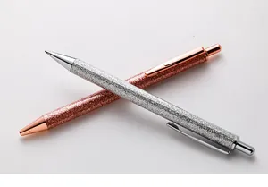 Detailed view of two glitter-covered retractable ballpoint pens in silver and rose gold