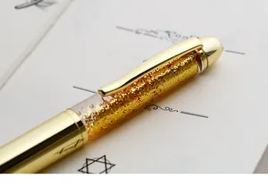 Close-up detail of the sparkling gold glitter quicksand inside the elegant transparent pen barrel