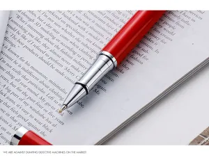Macro detail of a sleek red metal rollerball pen tip resting on an open magazine