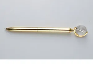 Detail view of an elegant gold metal ballpoint pen with a rotating crystal globe top.