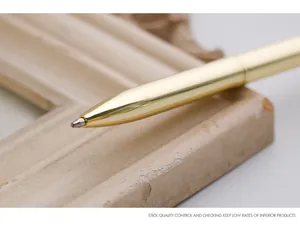 Close-up of the tip of a sleek golden metal ballpoint pen on a vintage frame.