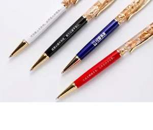 Macro view of four elegant gold leaf oil metal ballpoint pens showing custom engraving options.