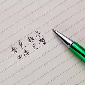 Professional green metallic ballpoint pen writing smoothly on lined notebook paper