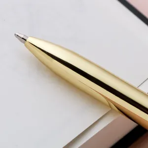 Macro view of luxury gold metal ballpoint pen resting on a white minimalist paper notebook