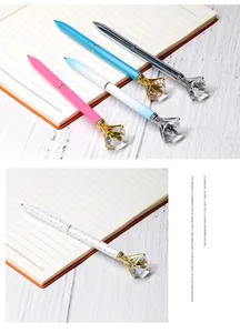 Close-up of creative metal ballpoint pens decorated with large crystal diamonds on top.