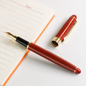 Elegant redwood fountain pen with gold metal trim resting on a lined notebook page