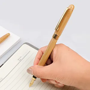 Elegant bamboo fountain pen with gold-plated trim being used on a notebook page