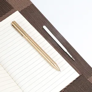 Premium white ballpoint pen refill shown with brass-colored metal pen on lined notebook