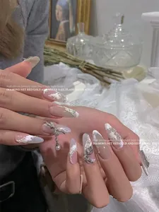 Close-up of elegant silver nail charms featuring pearl bows and intricate French designs
