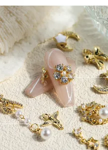 Detailed view of elegant gold nail art charms with pearls, bows, and sparkling zircons