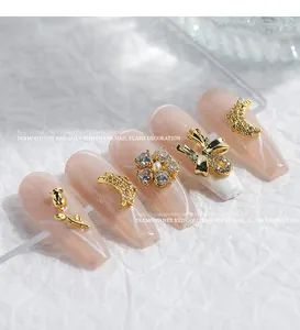 Detailed view of gold nail art charms with zircons and pearls on nude false nails