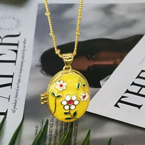 Close-up of yellow enamel oval locket necklace with delicate floral pattern detail
