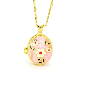 Detail view of a gold-plated oval locket necklace featuring pink enamel floral motifs.
