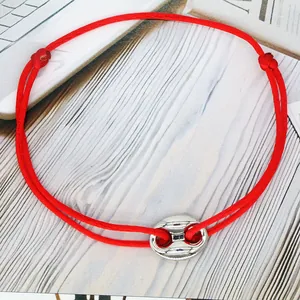 Detailed view of a minimalist red adjustable cord bracelet with a silver pig nose charm