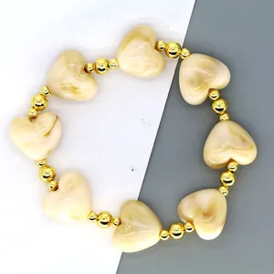 Detailed close-up of a French style bracelet with cream resin hearts and gold beads.