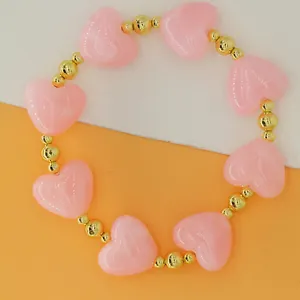 Macro detail of a sweet pink heart-shaped resin beaded bracelet with gold spacer beads