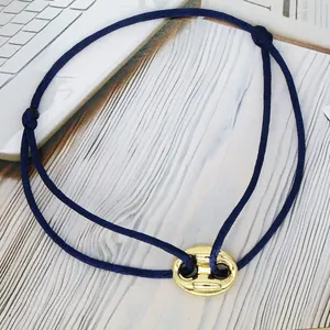 Macro view of blue cord bracelet featuring gold-toned pig nose charm detail