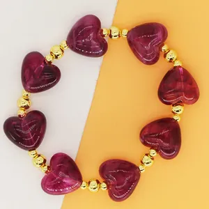 Macro detail view of purple resin heart beads and golden metallic balls on a bracelet