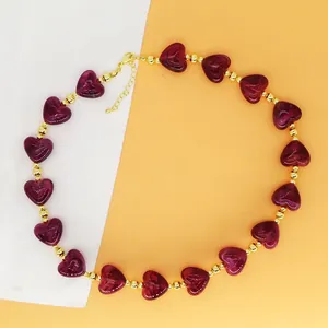 Detailed view of burgundy resin heart beads and gold beads on a choker necklace.