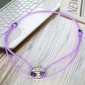 Close-up detail of purple adjustable cord friendship bracelet with silver pig nose charm