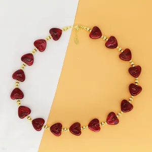 Detailed macro view of red resin heart-shaped beaded necklace with golden accents