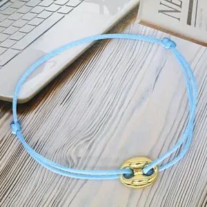 Close-up detail of sky blue adjustable woven cord bracelet with gold pig nose charm