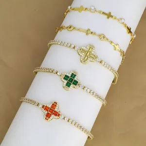Detail van vijf vergulde armbanden met kruis- en zirkonia-bloemmotieven op standaard