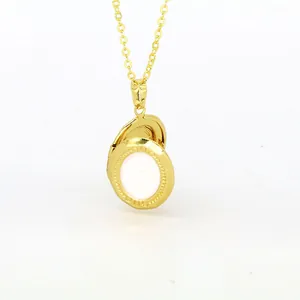 Close-up of golden oval locket necklace with white enamel center piece detail