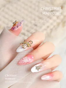 Detailed view of luxury Christmas nail art charms featuring golden bow and tree designs