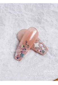 Macro view of iridescent hexagonal sequins and glitter on pink almond nail tips for DIY