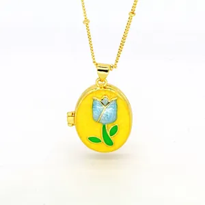 Detailed view of an 18k gold oval locket necklace featuring a blue enamel tulip design