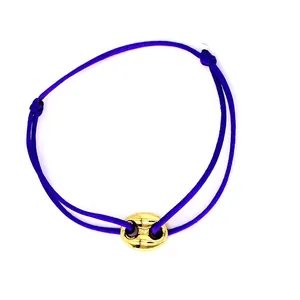 Adjustable purple cord friendship bracelet with gold pig nose charm on white background