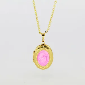 Close-up detail of a gold-plated oval locket pendant with swirling pink enamel inlay