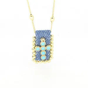 Dettaglio della collana con ciondolo a croce in denim boho vintage e pietre turchesi
