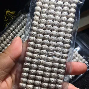 Close-up of high-density white Xingyue Bodhi beads with brown speckles in clear packaging.