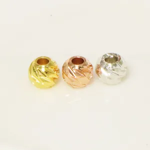 Close-up of textured spacer beads in yellow gold, rose gold, and silver finishes