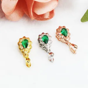 Nahaufnahme von Smaragdgrünen Anhänger-Clips in Gold-, Silber- und Roségold-Ausführung.