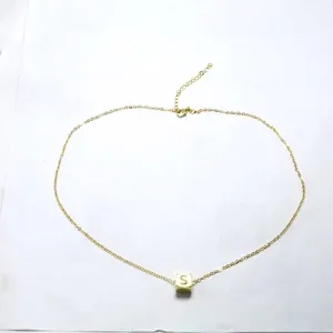 Detailansicht einer goldenen Halskette mit einem würfelförmigen Buchstaben-S-Anhänger