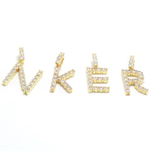 Detailansicht von vier goldfarbenen Buchstaben-Anhängern N, K, E, R mit klaren Zirkonia-Steinen.